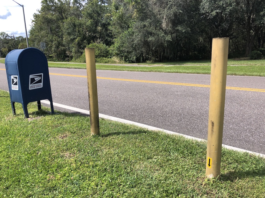 the mailbox along a road with a sticker on one of the poles